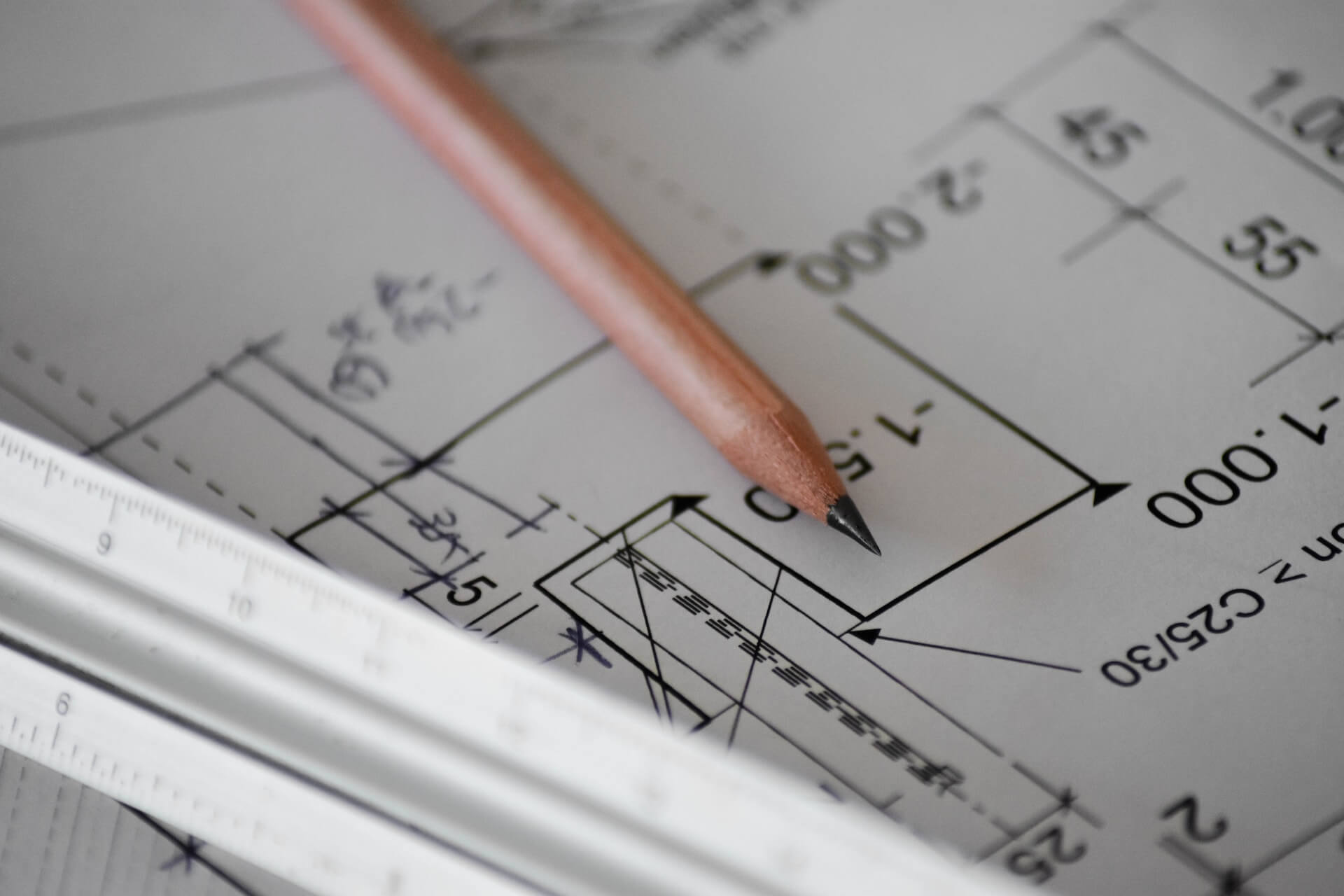 Un lápiz y una regla colocados sobre planos arquitectónicos, que simbolizan la precisión y la planificación en el diseño